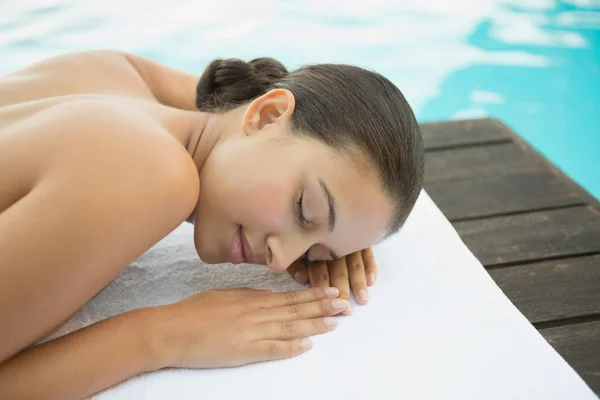 Friedliche brünette liegend auf handtuch pool — Stockfoto