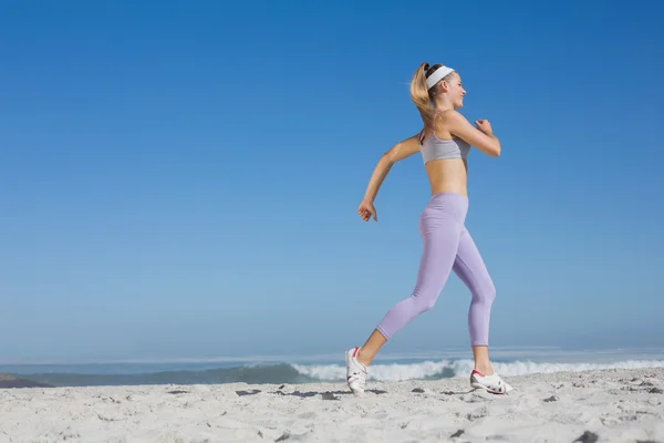 Sportieve blonde op het strand joggen — Stockfoto