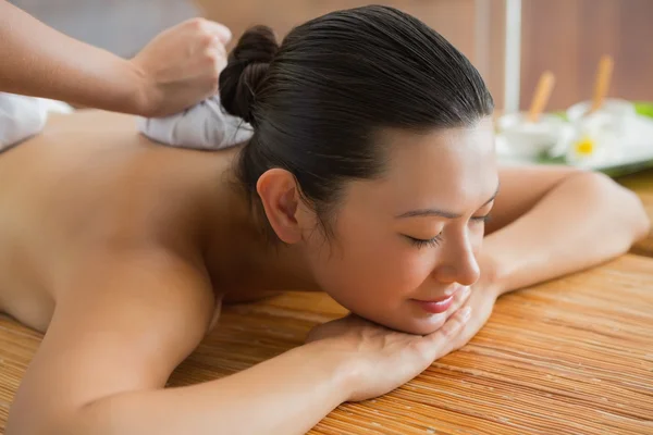 Brunett får en växtbaserade komprimerar massage — Stockfoto