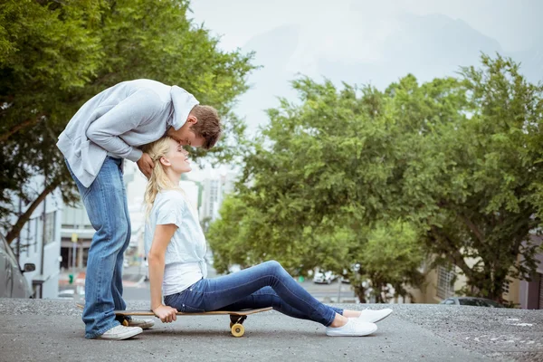 Блондинка на скейтборде с парнем целующим лоб — стоковое фото