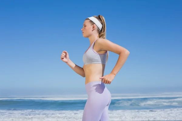 Sporty focused blonde jogging on beach — Stock Photo, Image