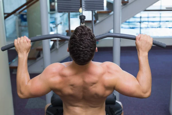 Bodybuilder using weight machine — Stock Photo, Image