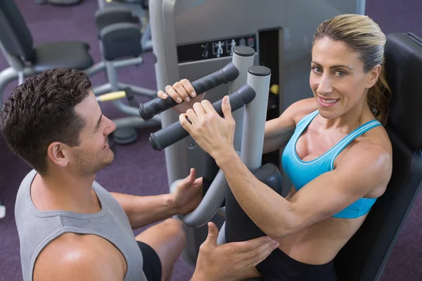 Trainer coaching bodybuilder using weight machine — Stock Photo, Image