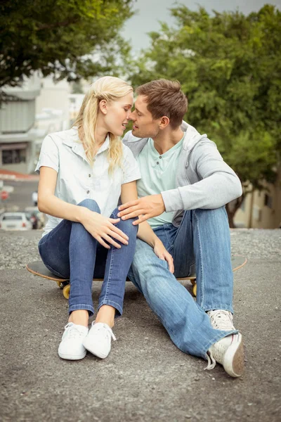 Couple de hanche assis sur skateboard baisers — Photo
