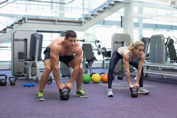 Bodybuilding man and woman lifting kettlebells — Stock Photo, Image