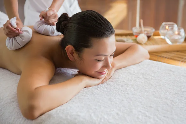 Brünette genießt eine Kräuterkompresse Massage — Stockfoto