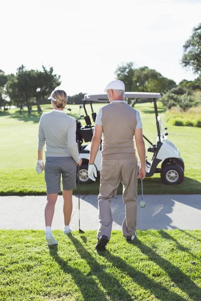 Golfing couple walking towards the buggy — Stock Photo, Image