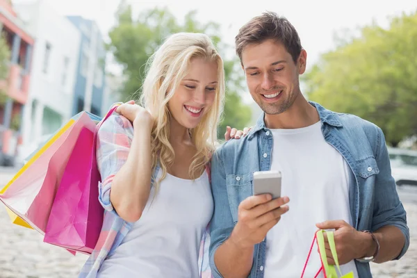 Casal olhando para smartphone em viagem de compras — Fotografia de Stock