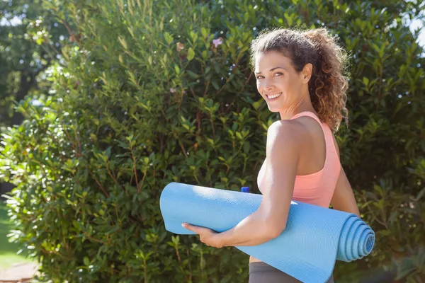 Woman holding exercise mat in the park — Stock Photo, Image