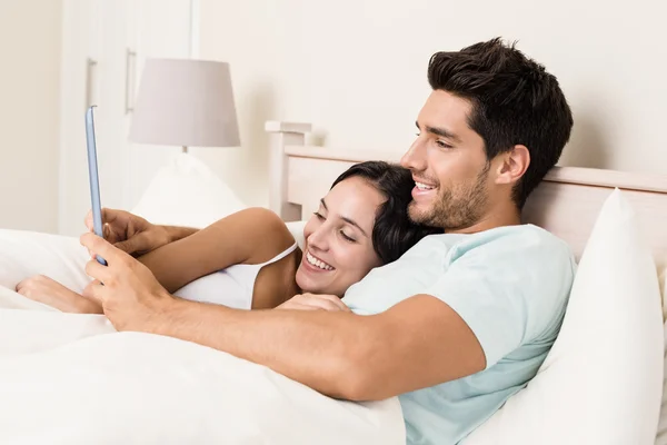 Casal deitado na cama com tablet pc — Fotografia de Stock