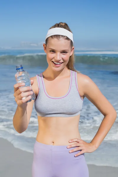 Sportovní blond zobrazeno láhev vody na pláži — Stock fotografie