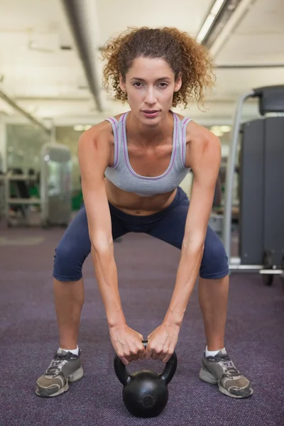 Fit woman squatting with kettlebell — Stock Photo, Image