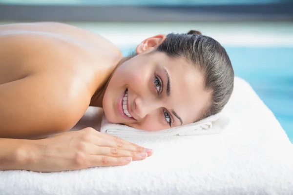 Brunette lying on massage table poolside — Stock Photo, Image