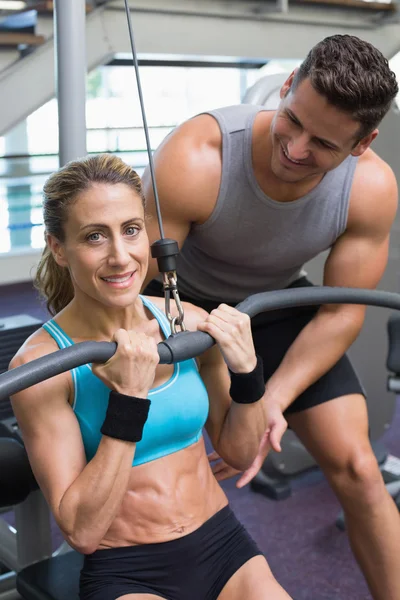 Female bodybuilder using weight machine — Stock Photo, Image