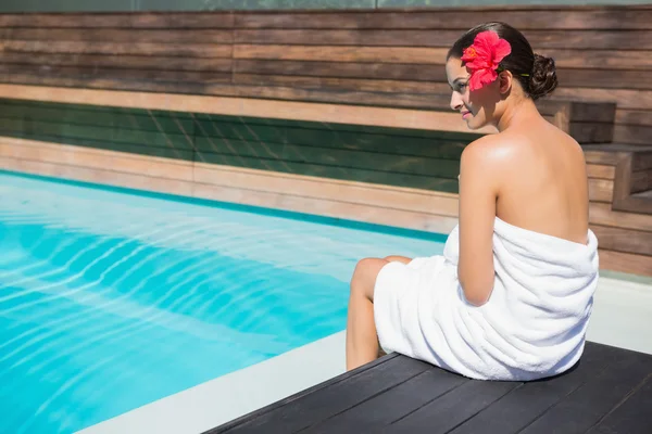 Morena en toalla sentada junto a la piscina — Foto de Stock
