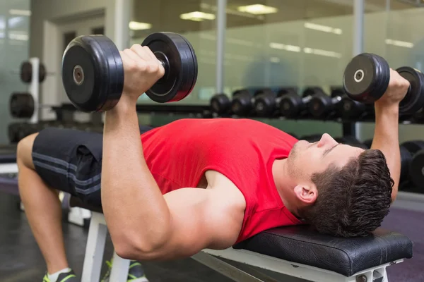 Bodybuilder couché sur banc haltères levage — Photo