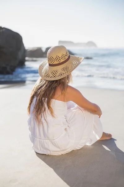Blonde in sundress zittend op het strand — Stockfoto