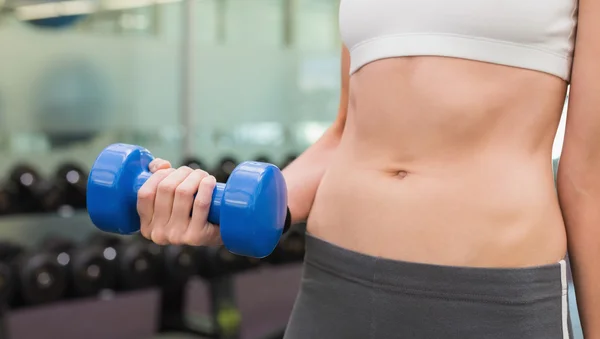 Fit woman holding blue dumbbell mid section — Stock Photo, Image