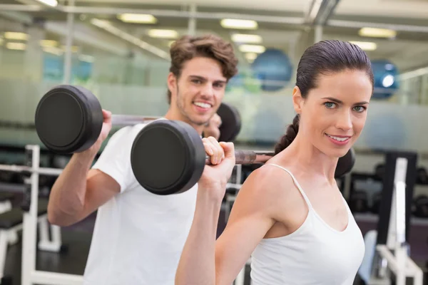 Fit couple lifting barbells together — Stock Photo, Image
