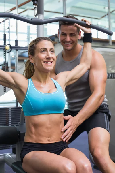 Female bodybuilder using weight machine — Stock Photo, Image