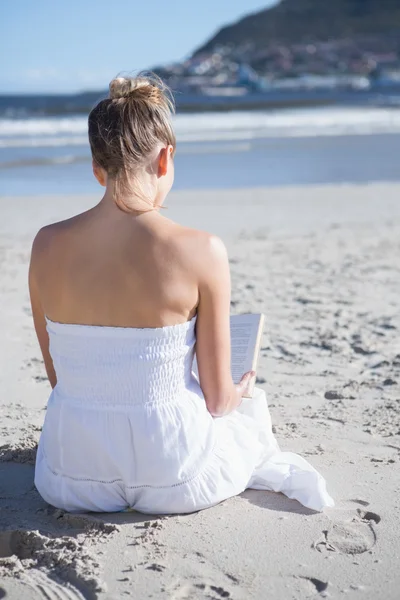 Blondin sitter på stranden läser bok — Stockfoto