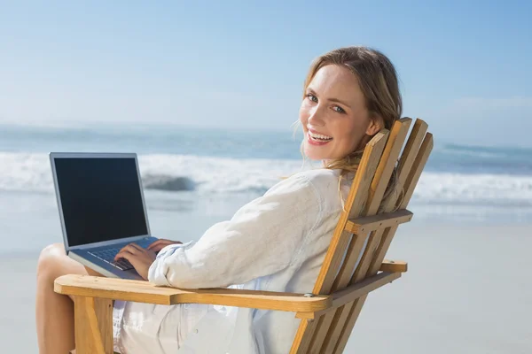 Blonde met behulp van laptop op strand — Stockfoto