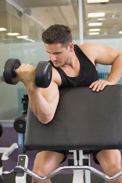 Focused bodybuilder lifting heavy black dumbbell — Stock Photo, Image