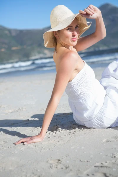Блондинка в белом платье сидит на пляже — стоковое фото