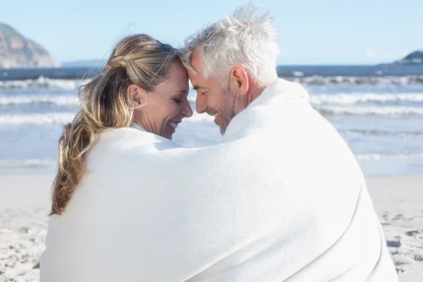 Пара сидящих на пляже под одеялом — стоковое фото