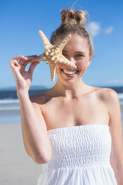 Блондинка, держащая звезду на пляже — стоковое фото