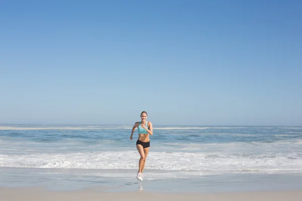 Fitte Frau joggt am Strand — Stockfoto