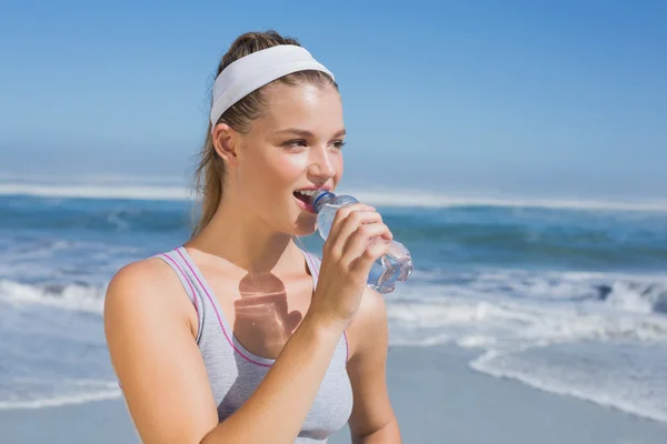 Bionda sportiva che beve acqua sulla spiaggia — Foto Stock