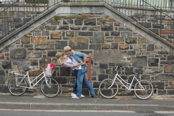 Hip couple dancing by wall with bikes — Stock Photo, Image