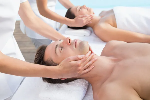 Couple enjoying head massages poolside — Stock Photo, Image