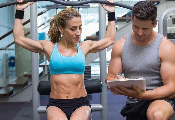 Female bodybuilder using weight machine — Stock Photo, Image