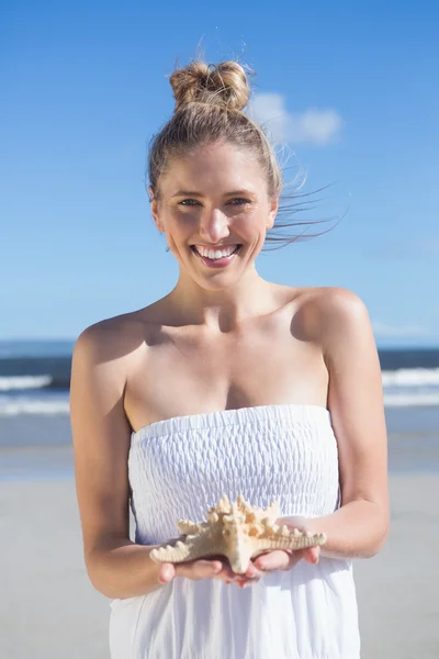 Rubia sosteniendo estrellas de mar en la playa —  Fotos de Stock