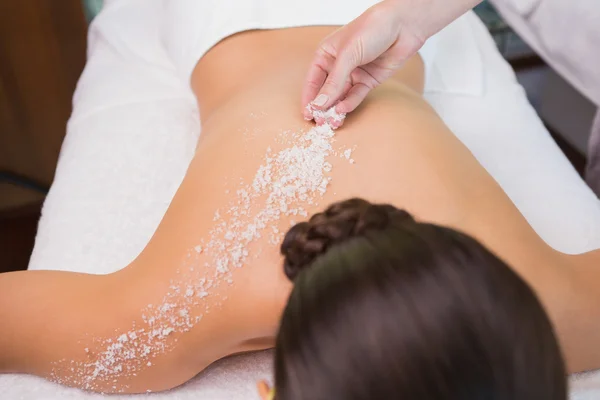 Therapist pouring salt scrub on womans back — Stock Photo, Image