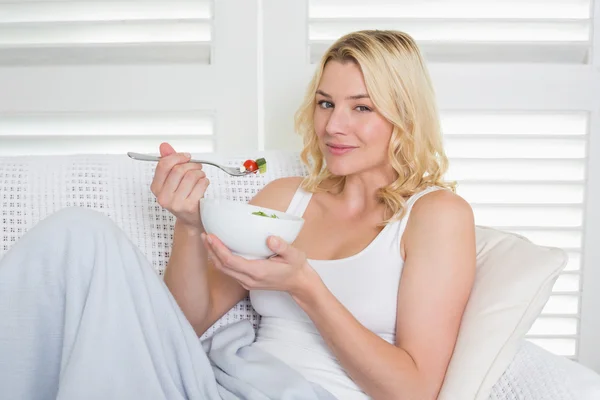 Rubia en el sofá comiendo ensalada —  Fotos de Stock