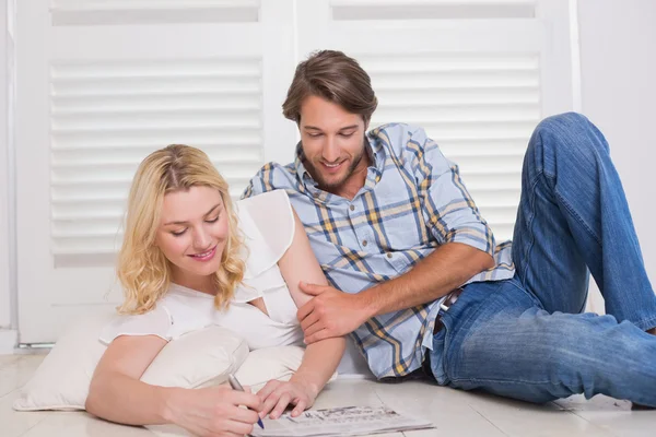 Pareja sentada en el suelo haciendo crucigrama — Foto de Stock