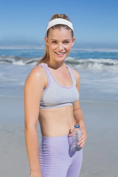Sportig blondin på stranden med en flaska — Stockfoto