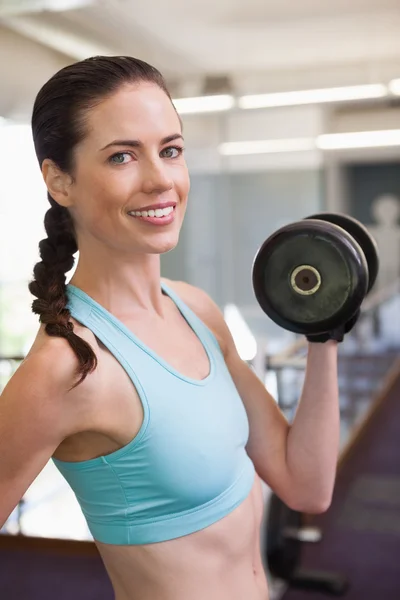 Smiling woman lifting heavy dumbbell — Stock Photo, Image