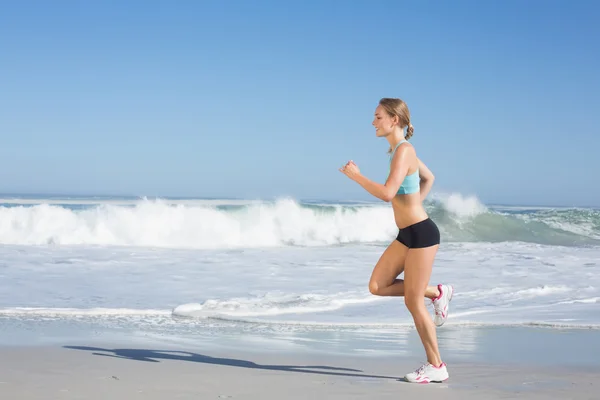 Fitte Frau joggt am Strand — Stockfoto