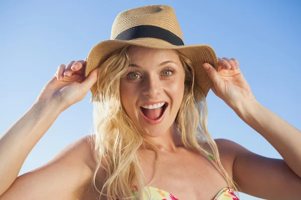 Blondin i stråhatt leende på stranden — Stockfoto