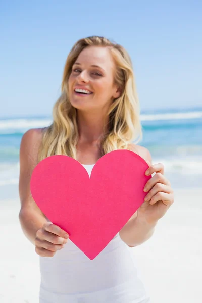 Rubia mostrando corazón rosa en la playa — Foto de Stock