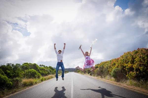 Excited couple jumping on road — Stock Photo, Image