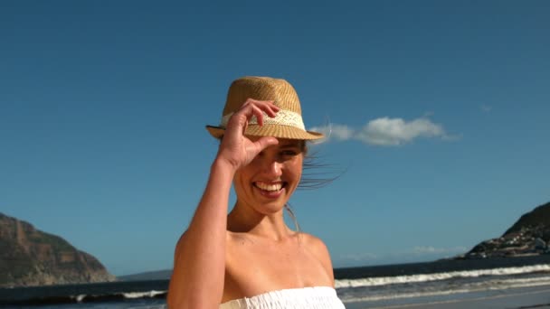 Lachende blonde opstijgen haar sunhat op het strand — Stockvideo