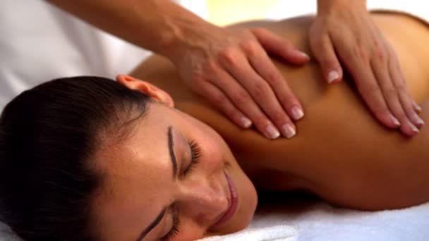Lächelnde Brünette genießt eine Massage im Wellnessbereich — Stockvideo