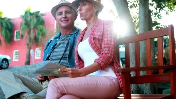 Paret sitter på bänken hålla karta — Stockvideo