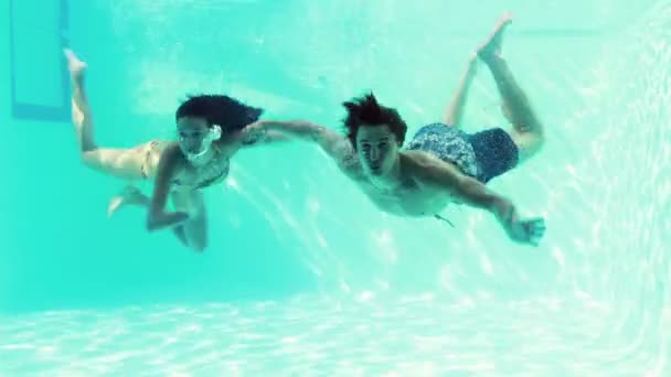 Happy couple jumping in swimming pool together — Stock Video