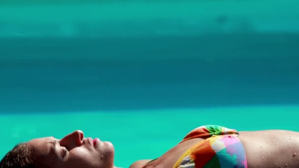 Сексуальна брюнетка лежить біля басейну засмагає — стокове відео